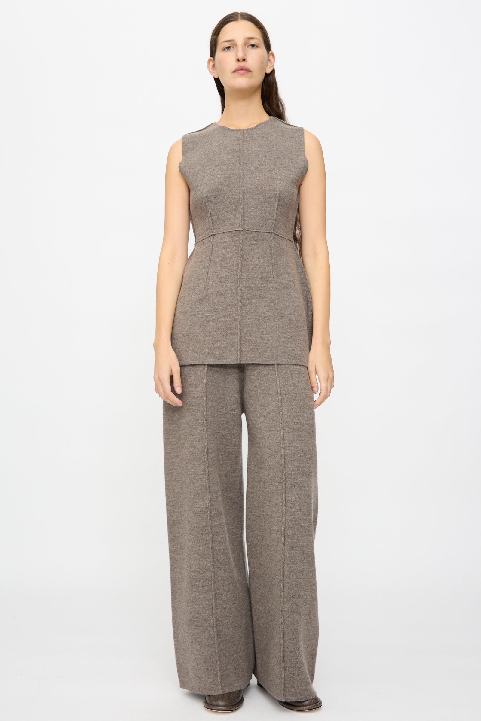 A woman stands facing forward against a plain white background, wearing the Lauren Manoogian Double Knit Trouser in Cinder with visible seam details and a matching sleeveless taupe top.