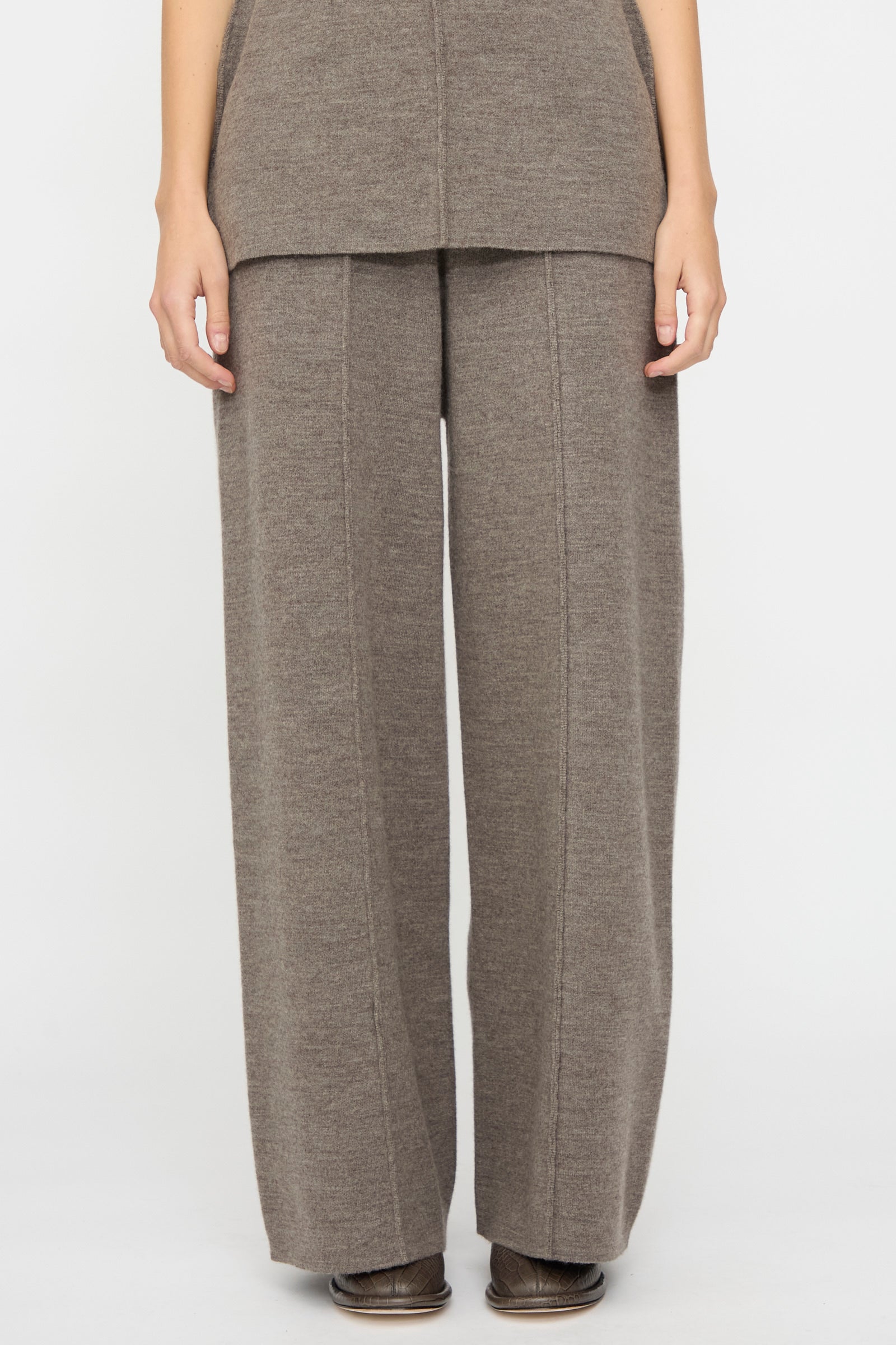 Person wearing Lauren Manoogian's Double Knit Trouser in Cinder—wide-leg, high-waisted merino wool pants—with a matching long sweater, standing against a plain white background.
