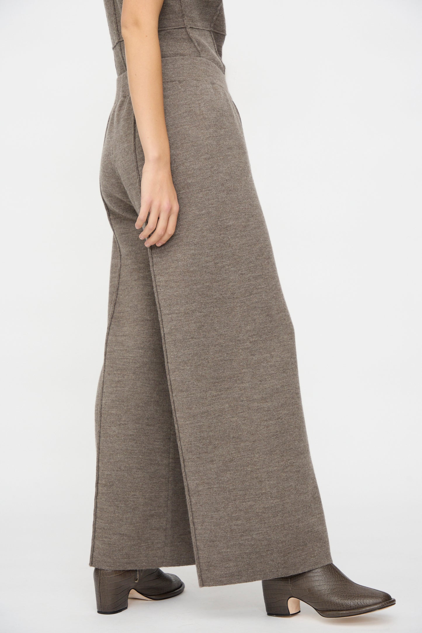 Model wears the Lauren Manoogian Double Knit Trouser in Cinder with dark brown ankle boots, shown from the side against a plain white background.