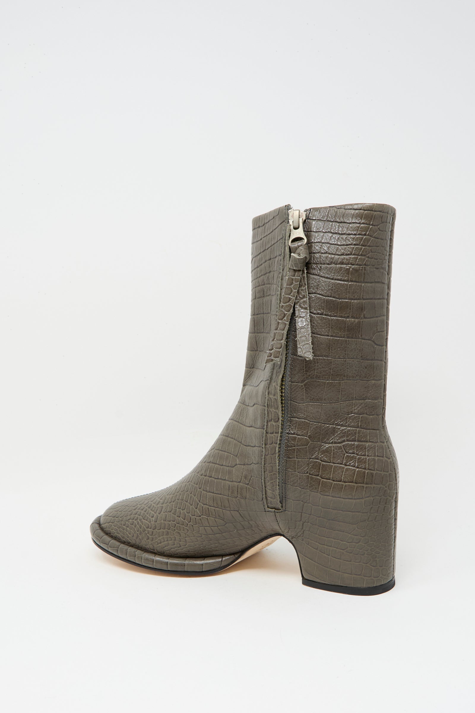 The Lauren Manoogian Embossed Arch Boot in Coal is a gray, above-ankle, crocodile-textured boot with a side zipper and low block heel, handmade in Peru from vegetable-tanned leather and displayed on a white background.