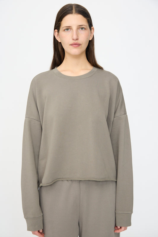 A person stands facing forward in a relaxed fit Lauren Manoogian Fleece Crewneck in Fatigue with matching pants, set against a plain background.