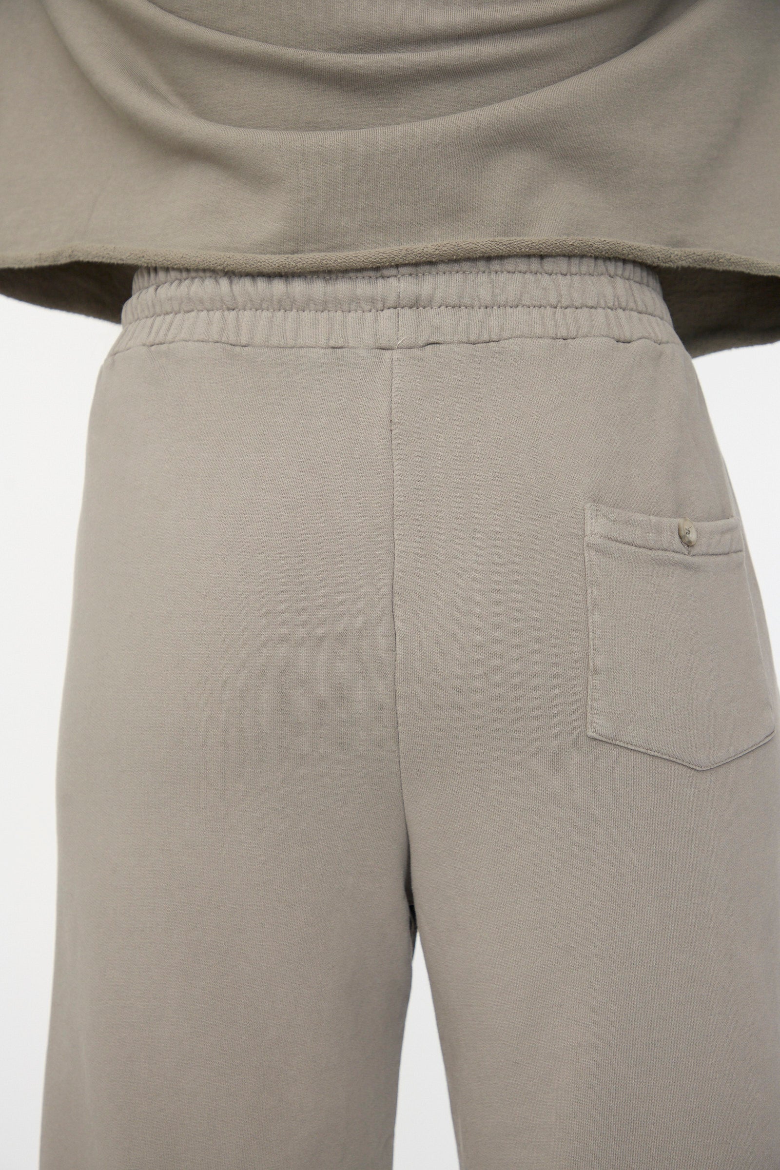Close-up of the back of a person wearing Lauren Manoogian's Fleece Pants in Fatigue, featuring a relaxed fit, elastic waistband, and a single buttoned pocket on the right side.