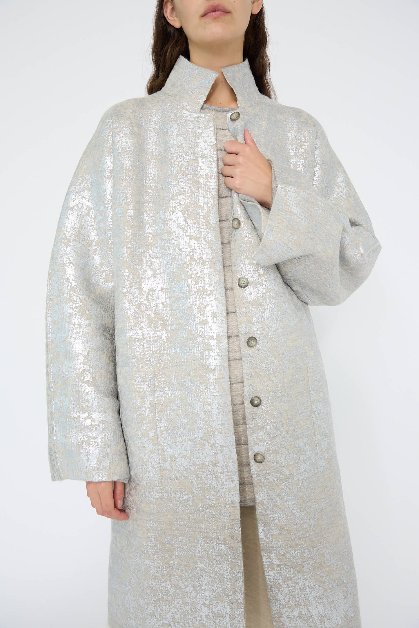 A person is wearing the Foil Car Coat in Silver Carrara by Lauren Manoogian, showcasing a relaxed fit with textured, buttoned details in light-colored fabric against a plain background.