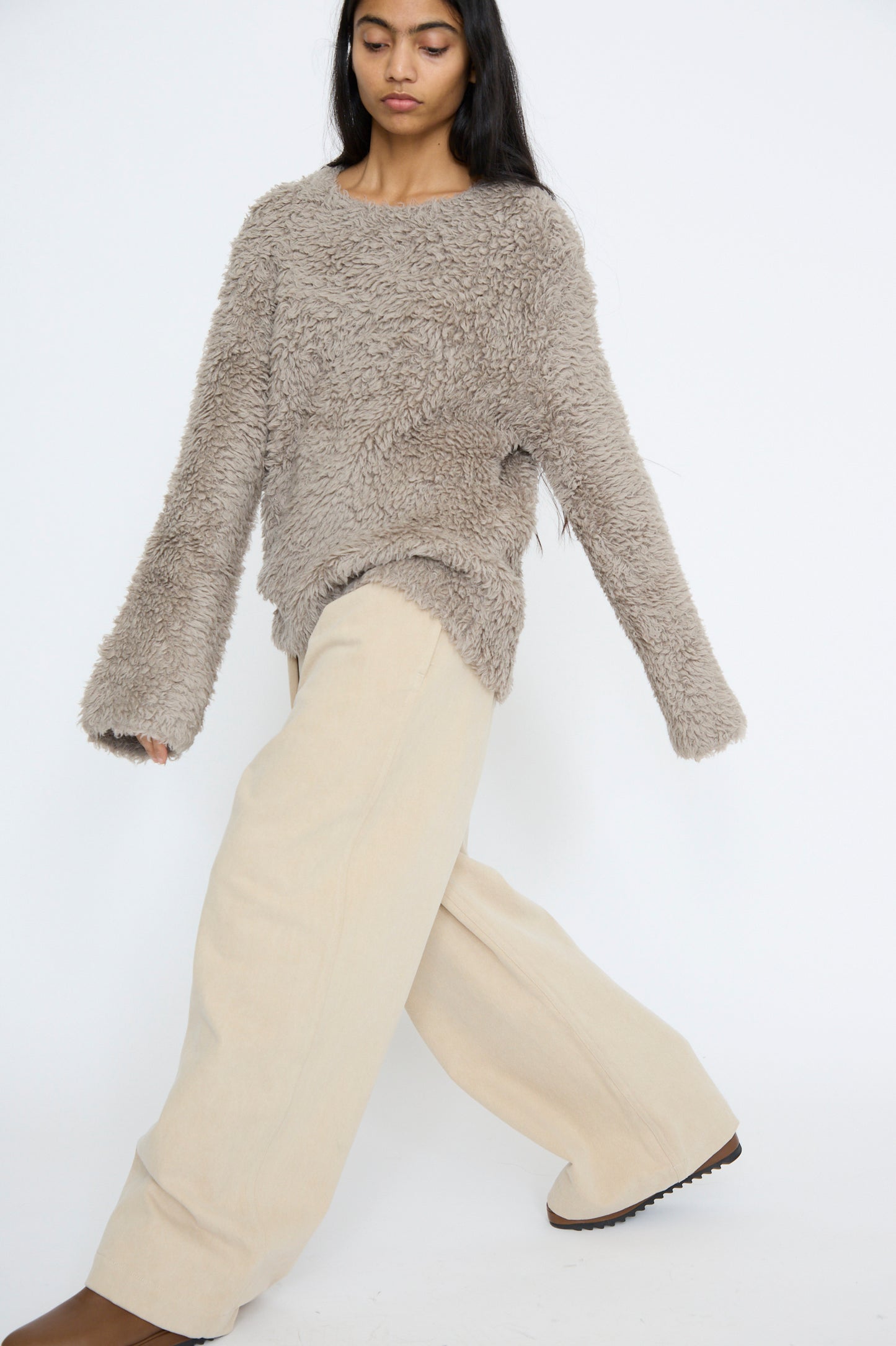 A person wearing a fuzzy gray sweater by Lauren Manoogian and Frame Jean in Khaki stands against a plain white background.