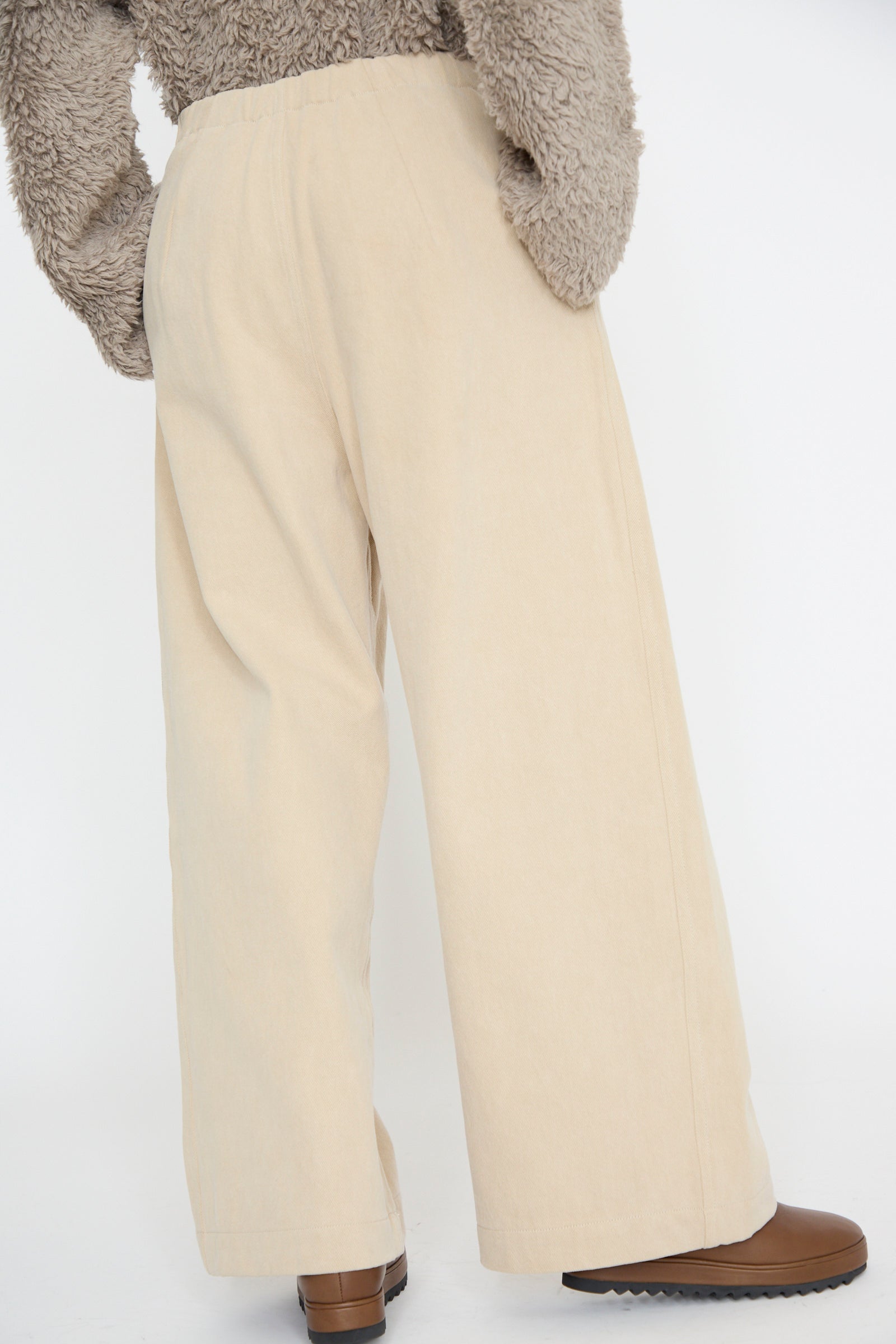 Model showcases the Frame Jean in Khaki by Lauren Manoogian, paired with brown shoes and a textured gray sweater, viewed from side and back angles.