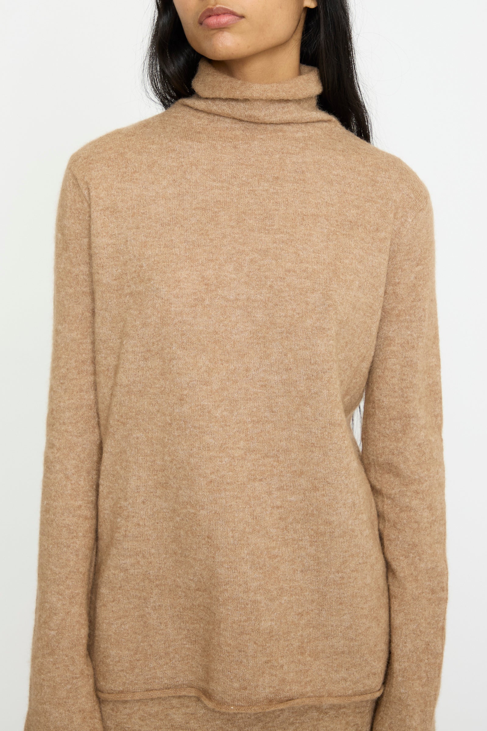 A person wearing the Lauren Manoogian Funnel Turtleneck in Camel, made from luxurious baby alpaca, stands against a plain background.