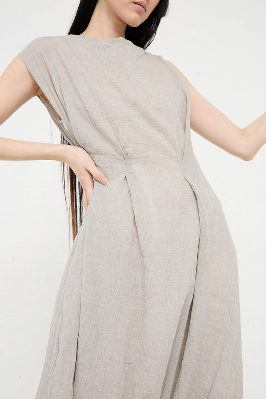 A woman in a Lauren Manoogian Gauze Twist Dress in Ash with a draped design, standing against a white background.