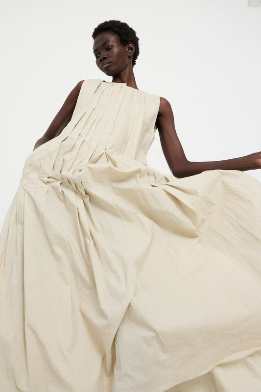 A person in the Hand Pleat Dress in Greige by Lauren Manoogian poses gracefully against a white background.