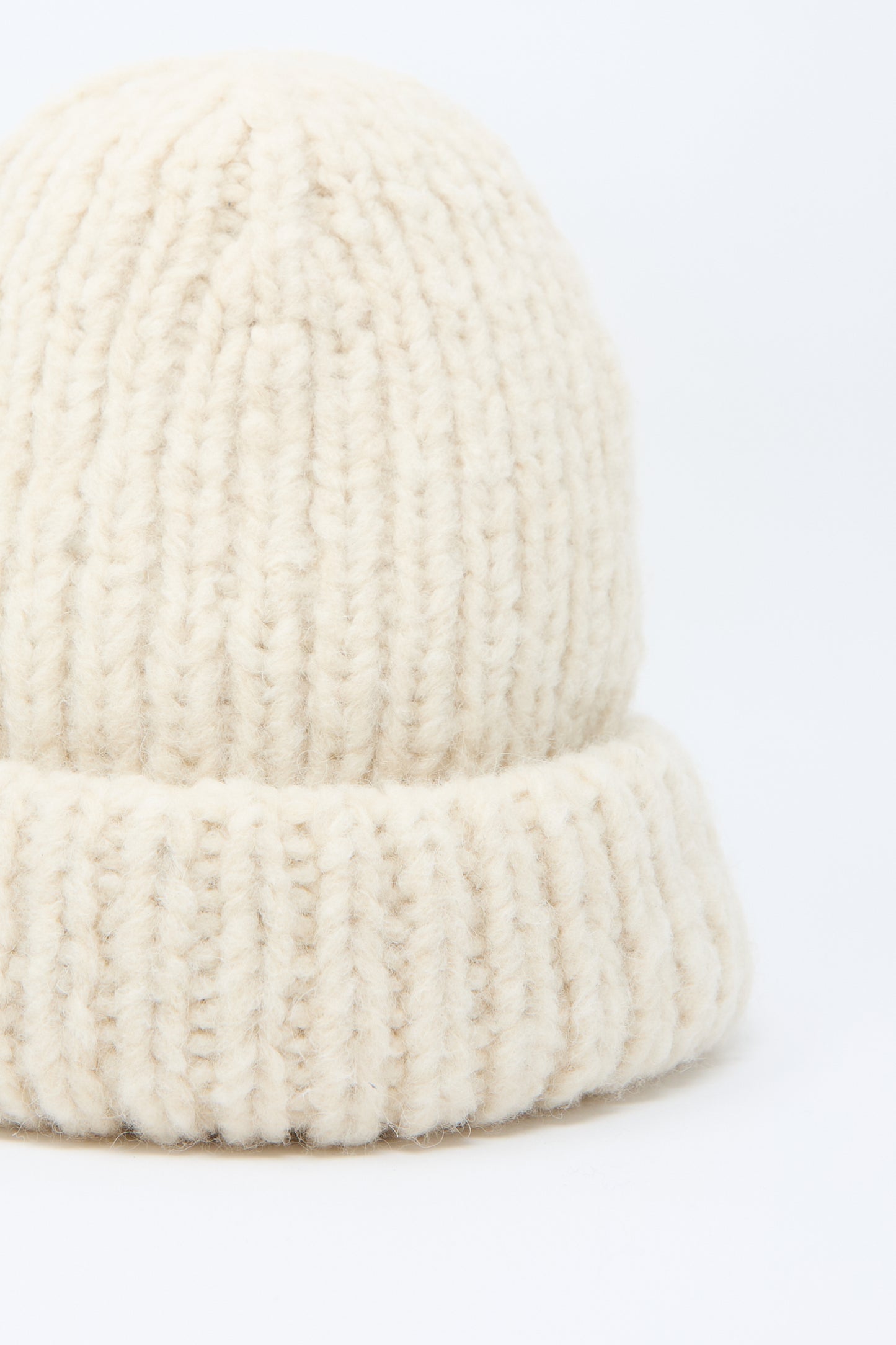 Close-up of the Lauren Manoogian Handknit Big Hat in Alabaster, featuring a chunky knit design with a folded brim, crafted meticulously from merino wool, set against a pristine white background.