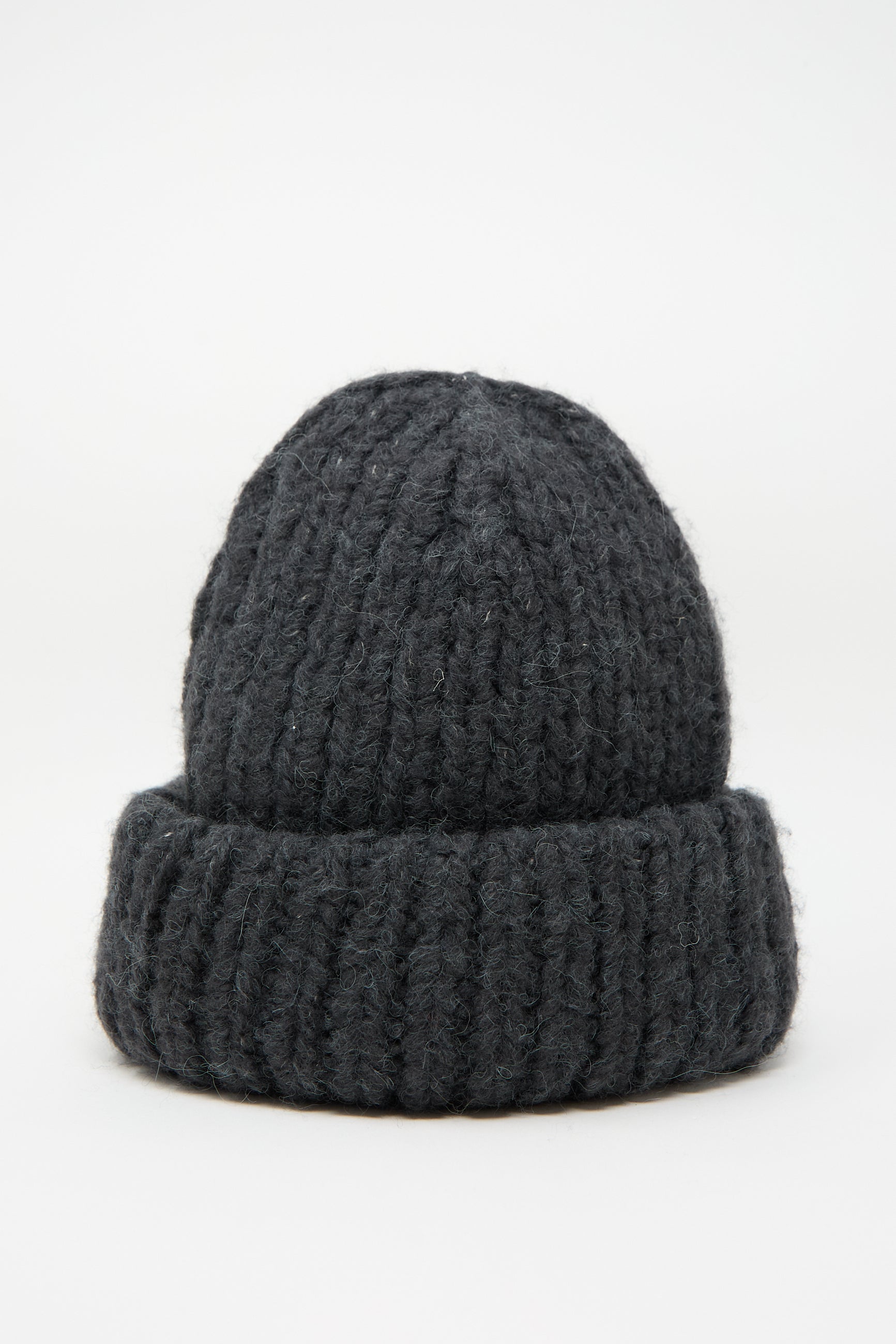 The Lauren Manoogian Handknit Big Hat in Ink, a luxurious alpaca/wool blend beanie with a rolled brim, is displayed against a plain white background. Made in Peru, this dark gray hat combines warmth and style effortlessly.