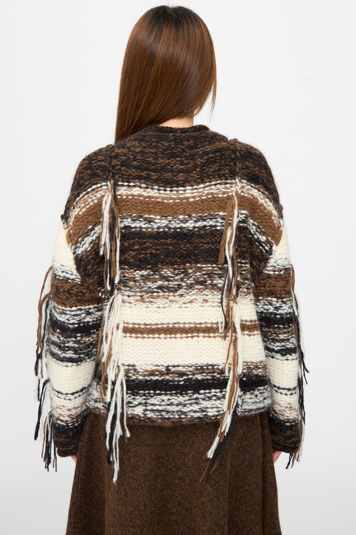 Back view of a person in a Lauren Manoogian Handknit Rio Rollneck in Marl Stripe, an oversized, rollneck chunky-knit sweater with horizontal stripes and hanging fringe.