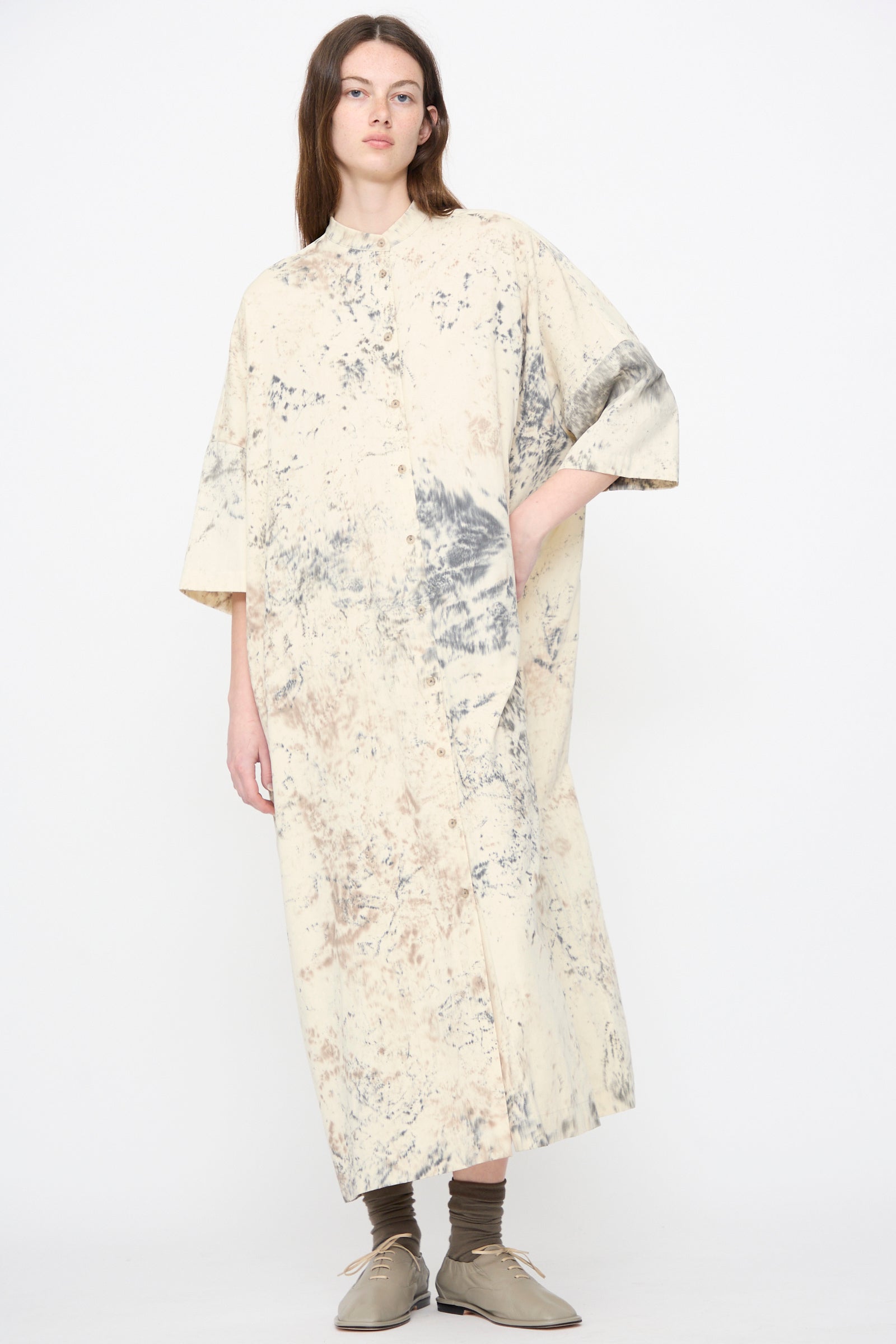 Model wears the Lauren Manoogian Handpaint Shirt Dress in Natural, a loose, ankle-length cream pima cotton dress featuring a gray and beige abstract pattern. 