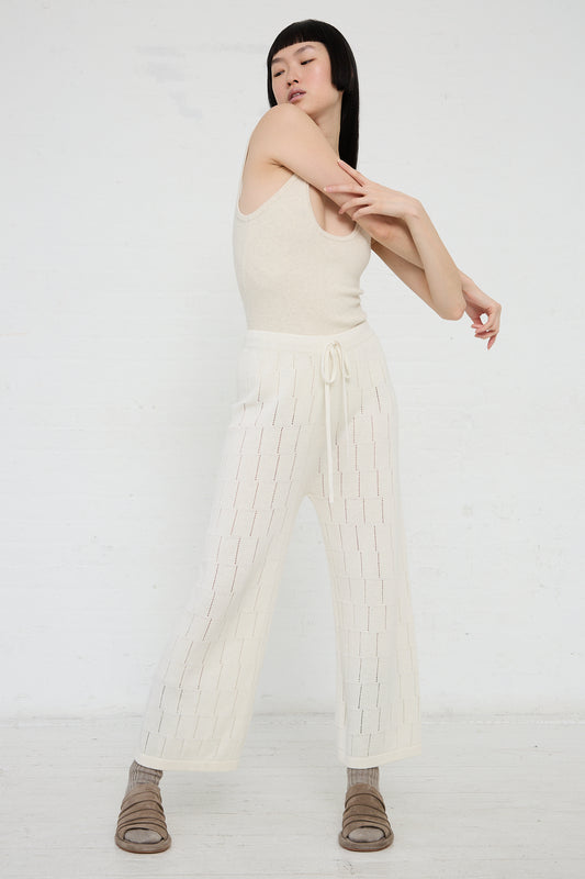 Sentence with replaced product: A woman posing in a neutral-colored sleeveless top and the Lauren Manoogian Lattice Pant in Bone, made from a pima cotton linen blend, paired with brown shoes, on a blank background.