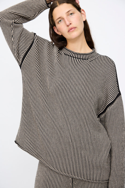 Person wearing the Lauren Manoogian Linea Rollneck in Black Melange and Sisal, an oversized pima cotton sweater with black and beige stripes, paired with matching pants, standing against a plain background.