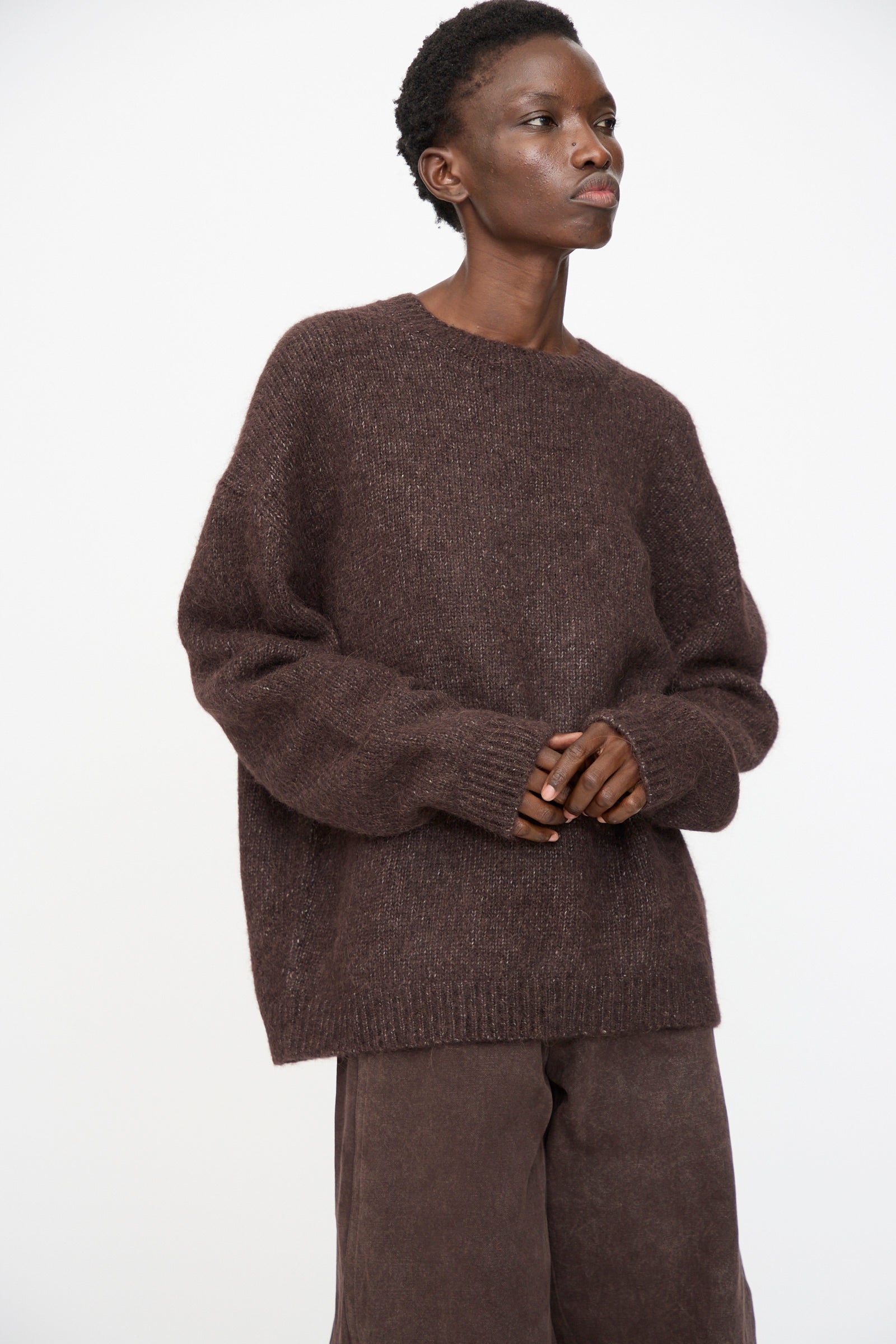 A person wears the Lauren Manoogian Loft Crewneck in Soil with brown pants, standing against a plain white background.