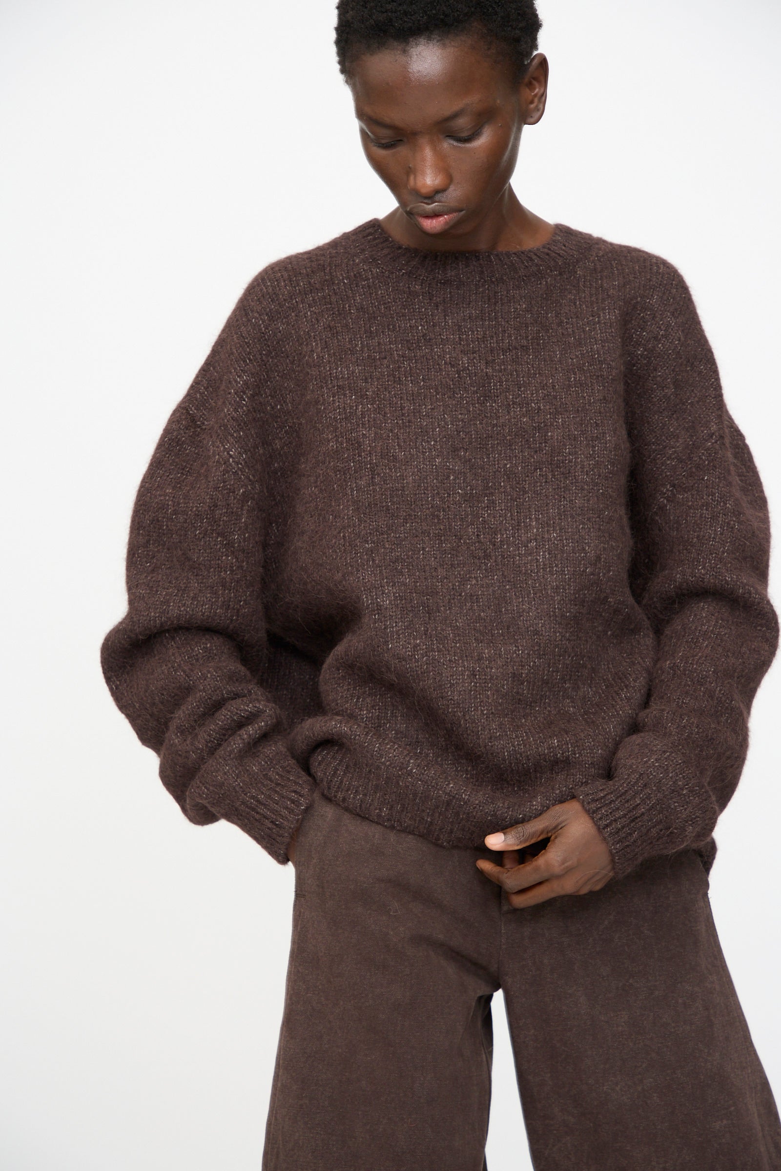 Person wears the Lauren Manoogian Loft Crewneck in Soil, paired with matching brown pants, standing against a plain light background.