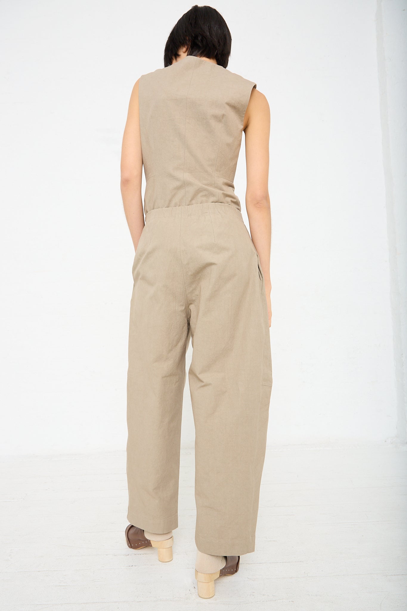The back view of a woman in a relaxed fit New Structure Pant in Drab (Olive Brown) with an elasticated waist by Lauren Manoogian. The model is wearing a matching top. Full length.