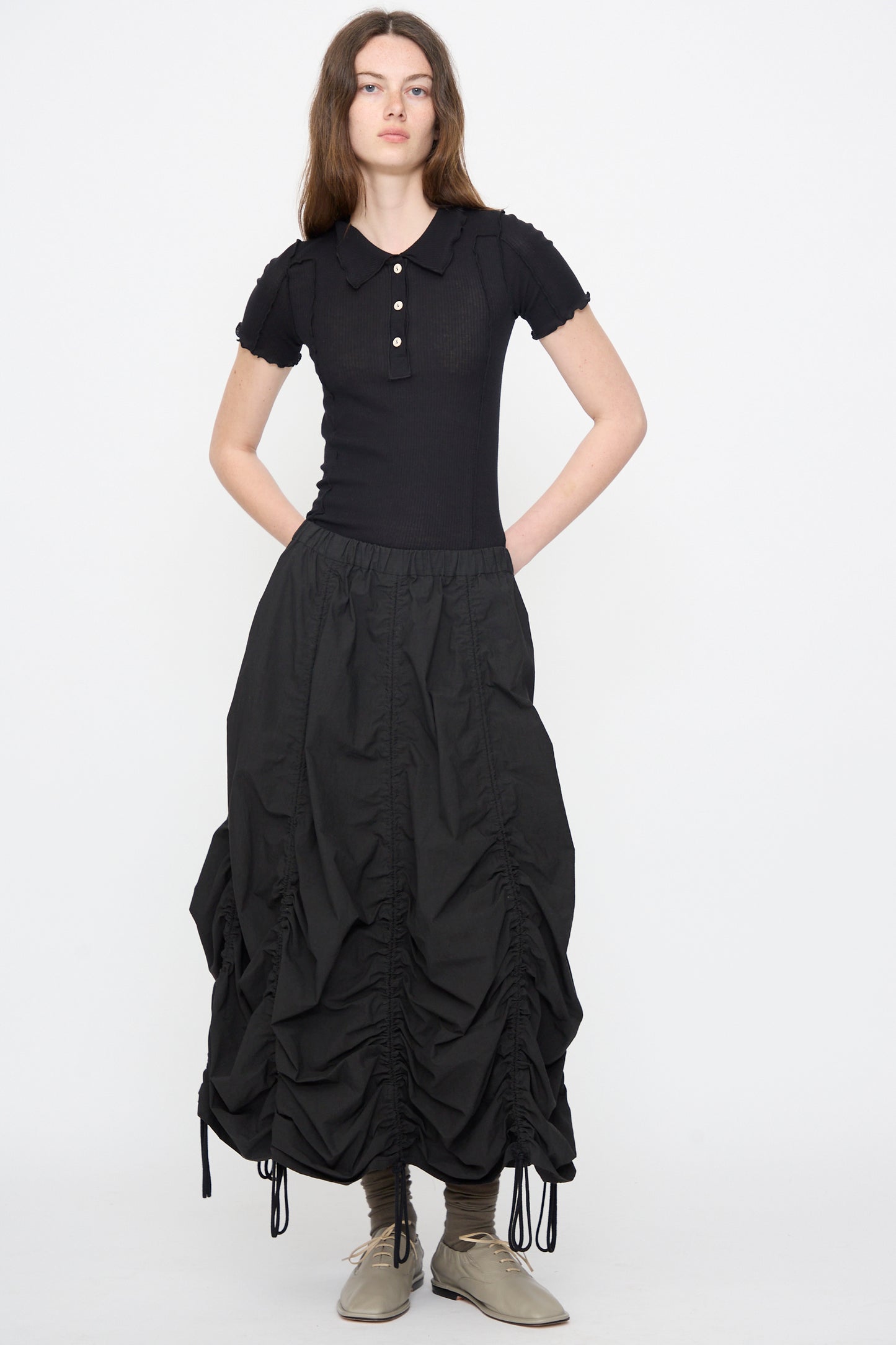 Woman in black short-sleeve collared shirt paired with the Parachute Skirt in Black by Lauren Manoogian, a midi skirt featuring subtle ruching.