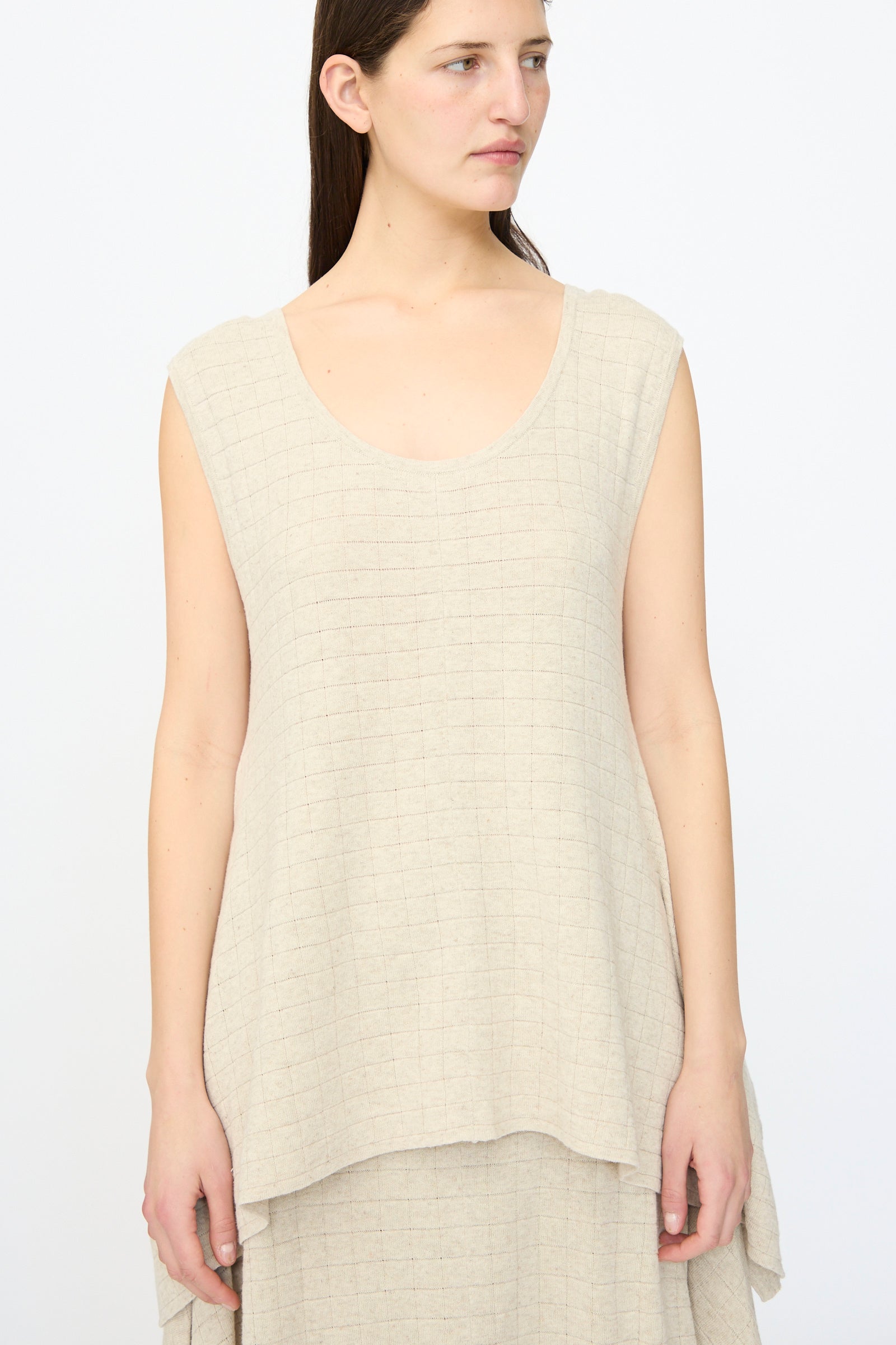 Woman wearing the Lauren Manoogian Planes Tank in Flax, a sleeveless beige linen top with textured fabric, relaxed fit, and scoop neckline, standing against a plain light background.