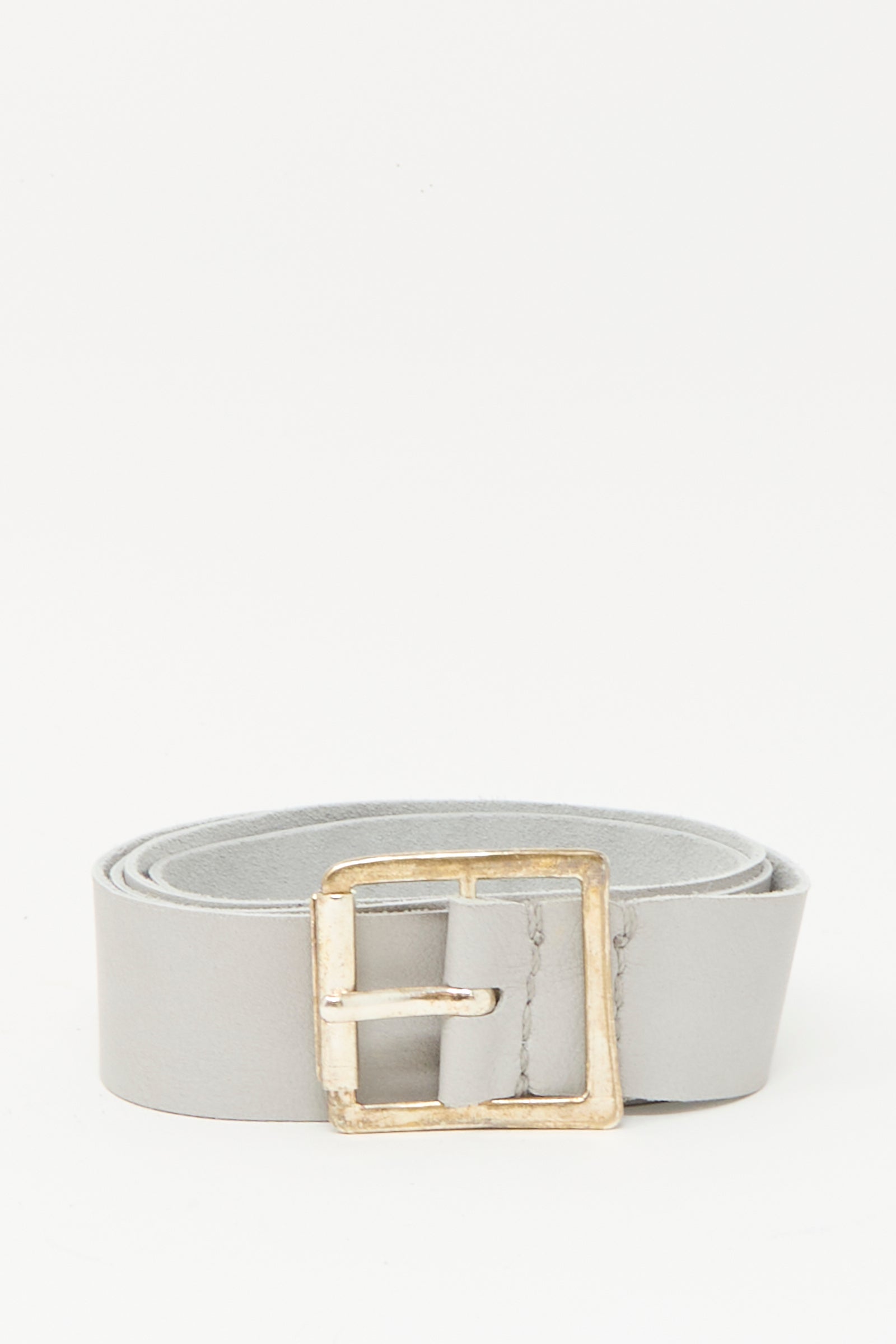 The Lauren Manoogian Plata Belt in Gris, featuring a handmade silver buckle and crafted from light gray leather in Peru, is shown rolled up against a plain white background.