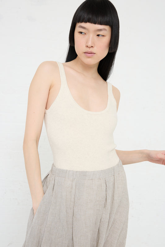 Woman posing in a Rib Bodysuit in Hessian (cream) pima cotton bodysuit and gray trousers by Lauren Manoogian against a white background.