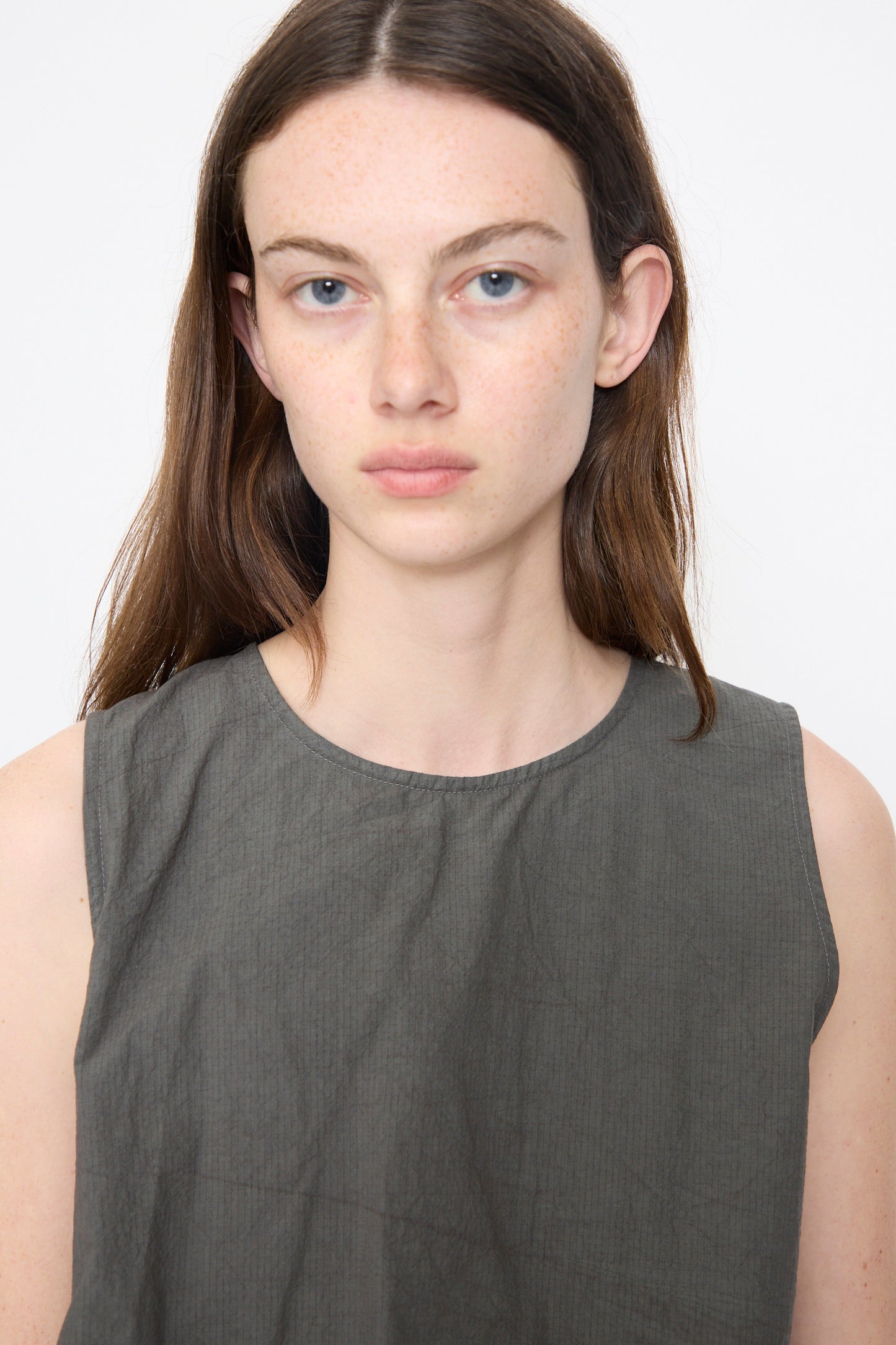 A model wears the Lauren Manoogian Ripstop Dress in Coal, a sleeveless crew-neck piece with an asymmetrical gathered silhouette and textured fabric, photographed from the chest up against a white background.