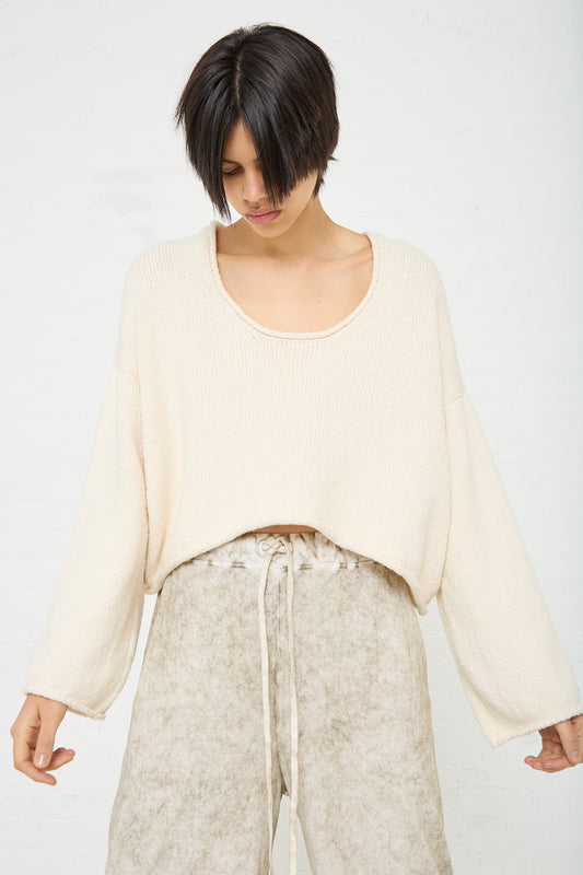 A woman wearing a Lauren Manoogian Roving U Neck Sweater in Raw White and tan pants.