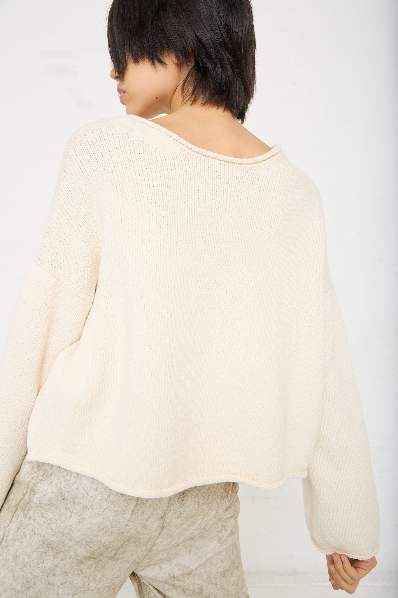The back of a woman wearing a Lauren Manoogian Roving U Neck Sweater in Raw White.