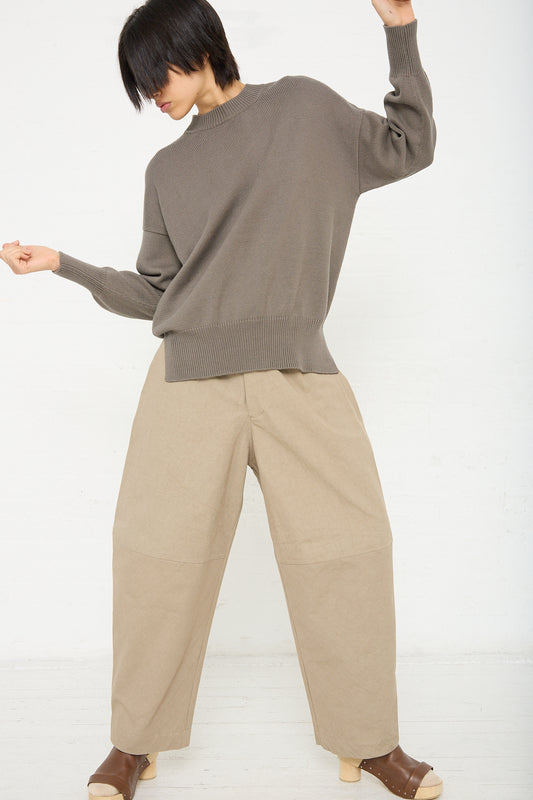 A woman in a Lauren Manoogian Simple Crewneck in Rock (Olive Brown) colored sweater with dropped shoulders. Front view and full length.