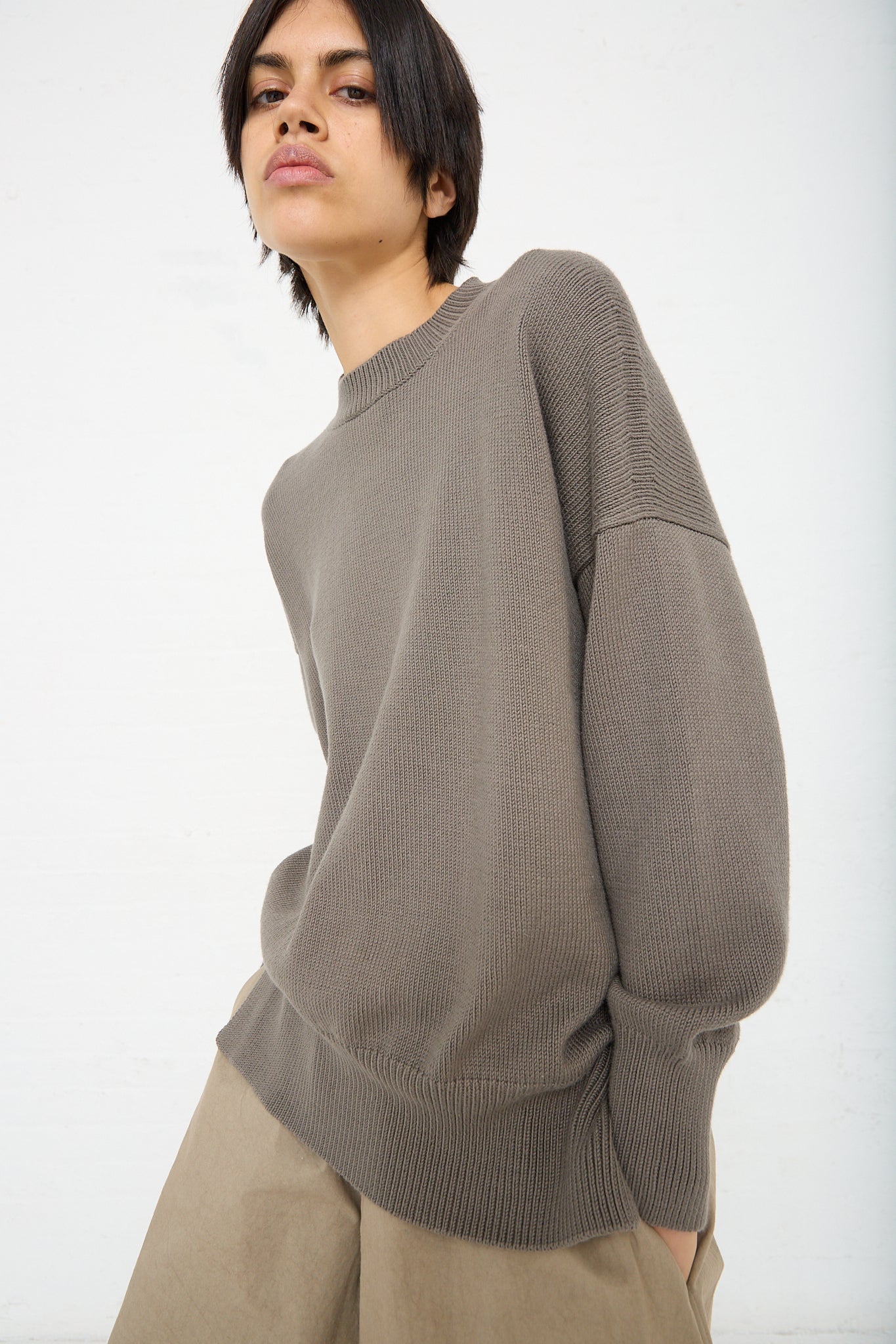 The model is wearing a Simple Crewneck in Rock (Olive Brown) by Lauren Manoogian and khaki pants. Front view.