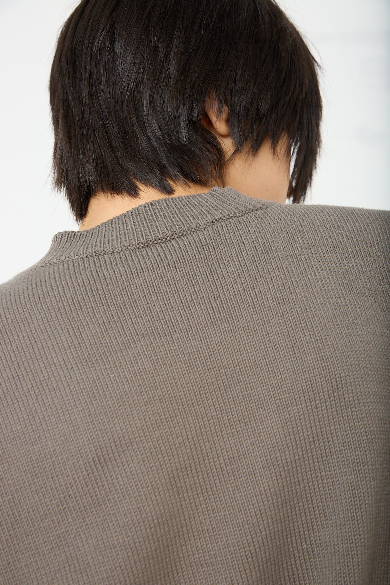 The back view of a woman wearing an olive brown colored pima cotton sweater by Lauren Manoogian. Up close.