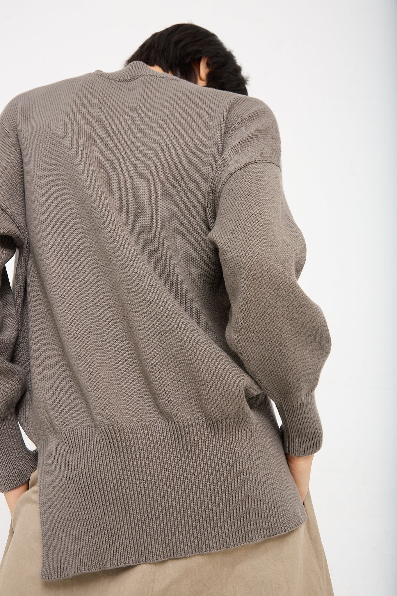 The back of a woman wearing a Lauren Manoogian Simple Crewneck in Rock (Olive Brown), made from pima cotton and paired with khaki pants.
