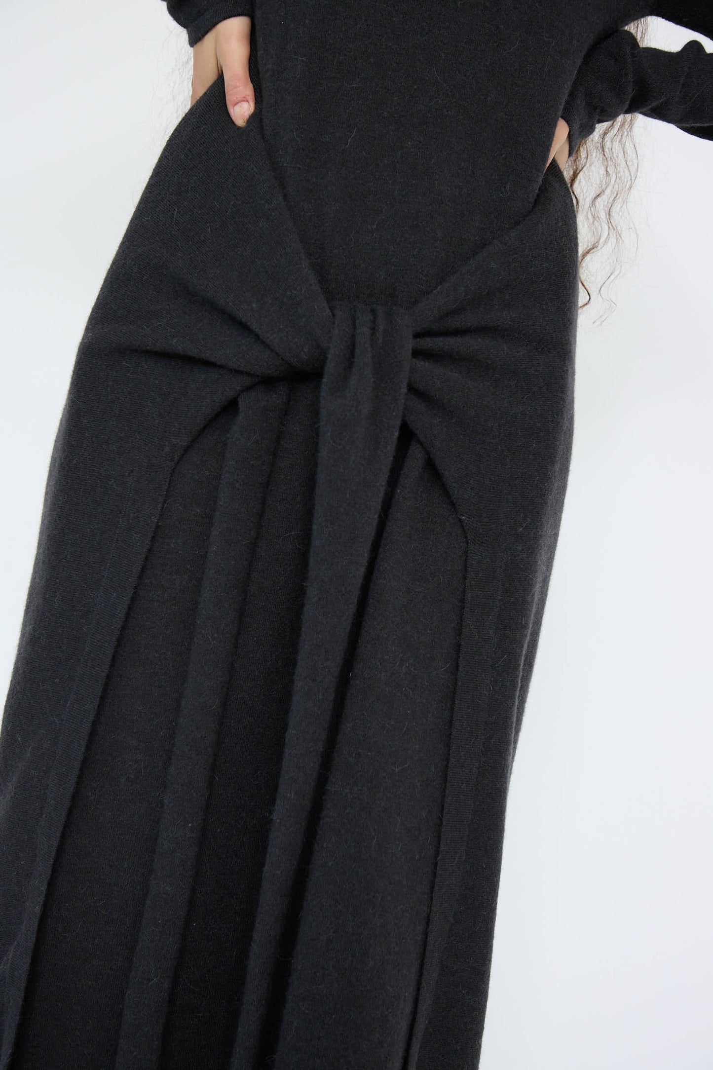 Close-up of a person wearing the Sleeves Dress in Ink by Lauren Manoogian, showcasing a central knot design near the waist. This black maxi dress is crafted from a soft wool and alpaca blend, providing a truly relaxed fit.