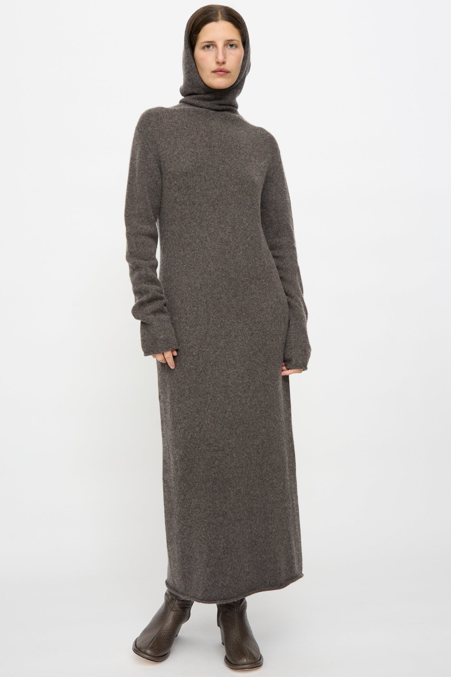 A person wearing Lauren Manoogian's Soft Balaclava Dress in Blackened with dark brown boots, standing against a plain white background.