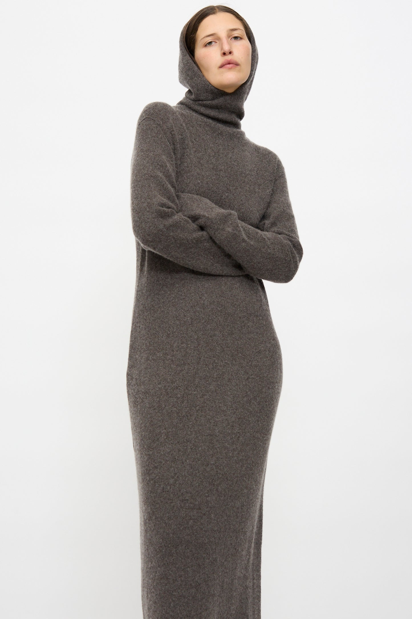 A person wears the Lauren Manoogian Soft Balaclava Dress in Blackened, standing with arms crossed against a plain white background.