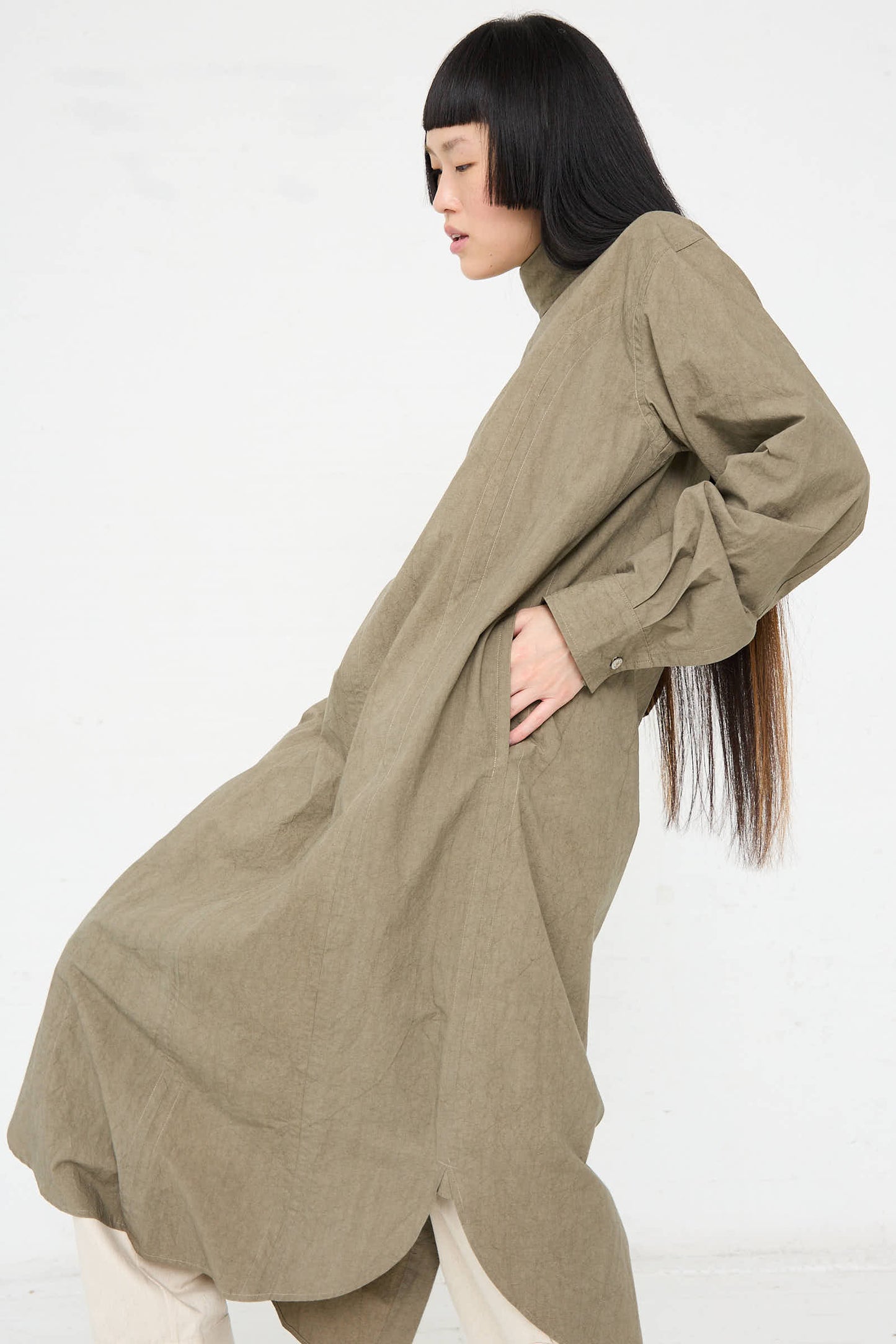 A person with long black hair wearing a relaxed fit, Soft Collar Shirt Dress in Clay by Lauren Manoogian stands sideways against a plain white background.