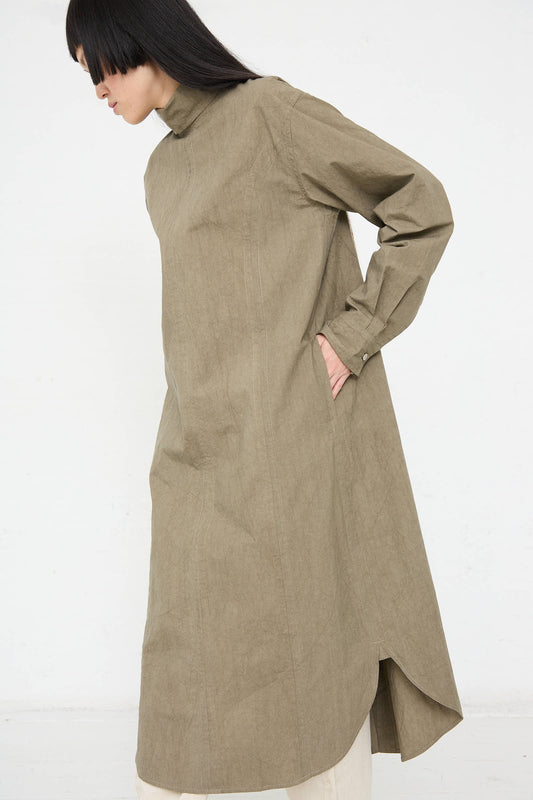 Person wearing the Lauren Manoogian Soft Collar Shirt Dress in Clay with buttoned cuffs and hands in pockets, standing against a plain white background.