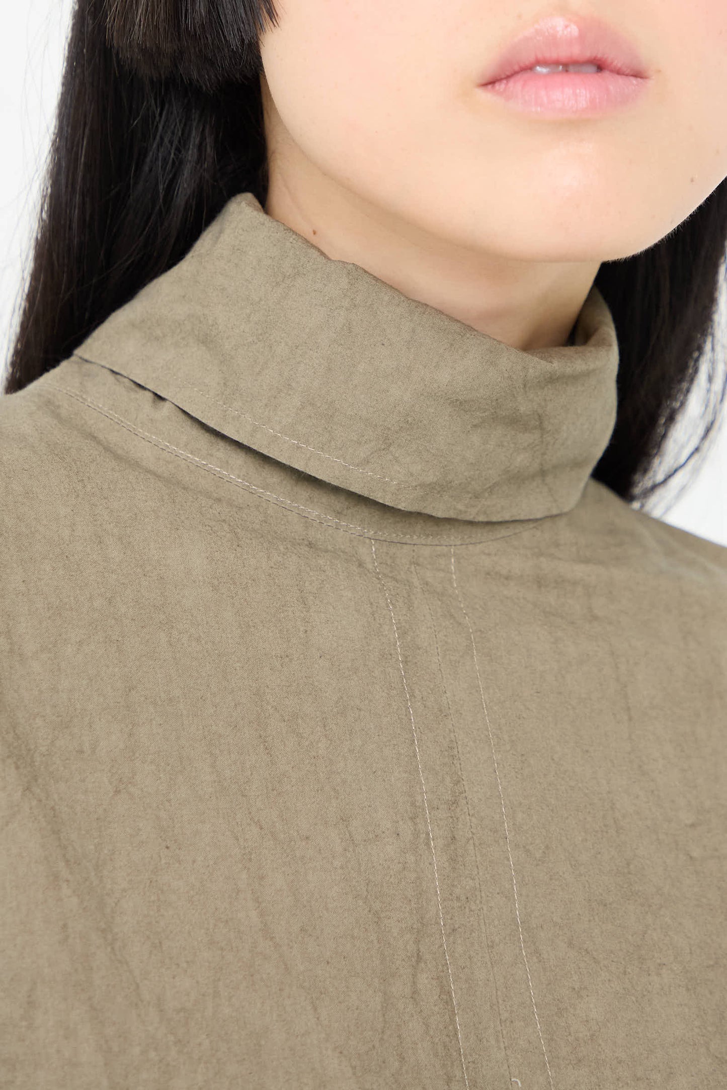 Close-up of a person wearing the "Soft Collar Shirt Dress in Clay" by Lauren Manoogian. Only the lower half of their face is visible, and they have straight, dark hair.