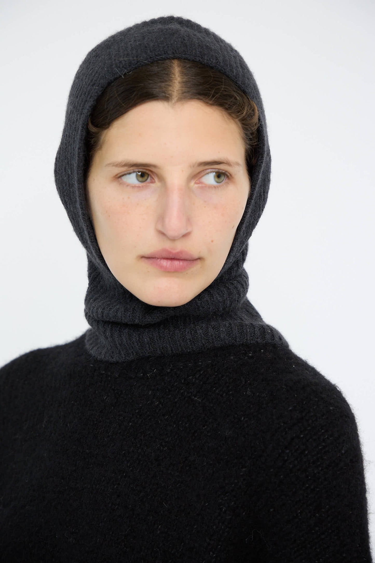 Person wearing the Soft Rib Balaclava in Ink by Lauren Manoogian, gazing to the side against a plain background.