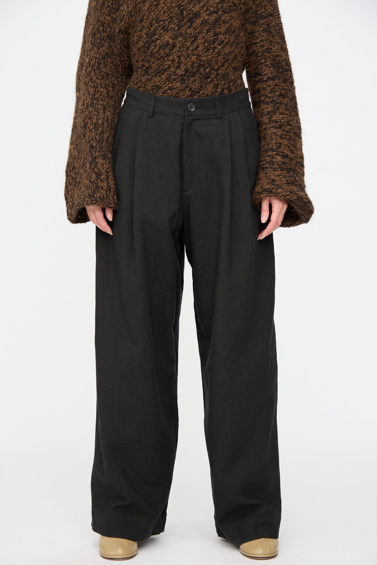 Lauren Manoogian Soft Trouser in black cotton blend, featuring a relaxed wide-leg fit and pleated waist, worn with a brown textured sweater.