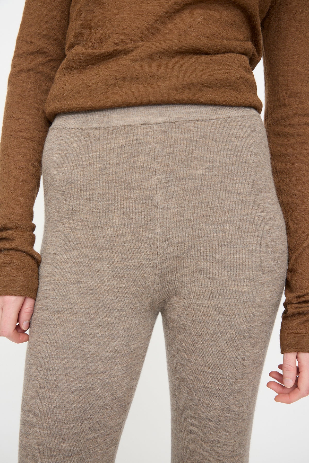 A person wearing a brown long-sleeve top and the Lauren Manoogian Stirrup Legging in Grey Melange, photographed from shoulders to upper thighs against a plain background.