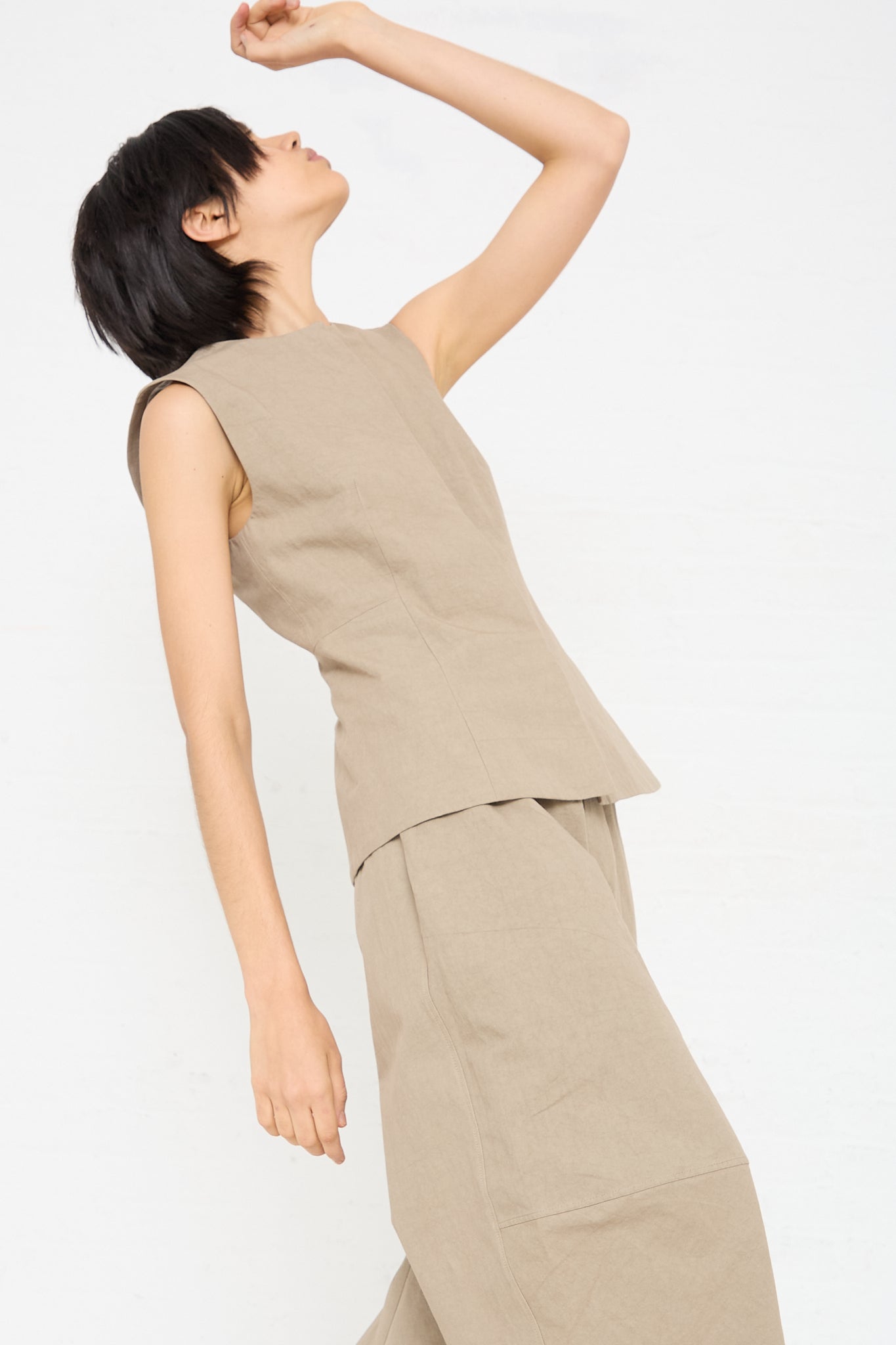 A woman wearing a Lauren Manoogian Structure Bodice in Drab Olive Brown) sleeveless top with matching pants. Profile view.