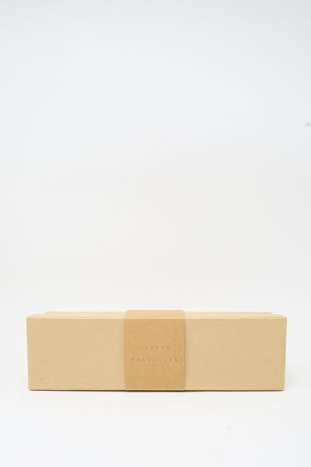 A rectangular, closed cardboard box with a minimalist design and a centered paper band, placed against a plain white background—perfect for gifting the Lauren Manoogian Tall Sock Set in Mix, premium baby alpaca socks made in Peru.