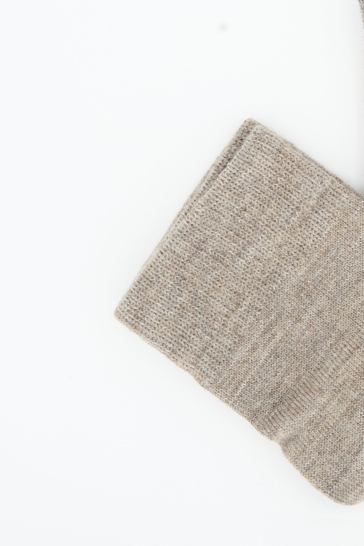 Close-up of a beige knit fabric, likely the cuff of a sock from the Tall Sock Set in Mix by Lauren Manoogian, positioned against a plain white background. The texture suggests it could be crafted from high-quality baby alpaca and made in Peru.