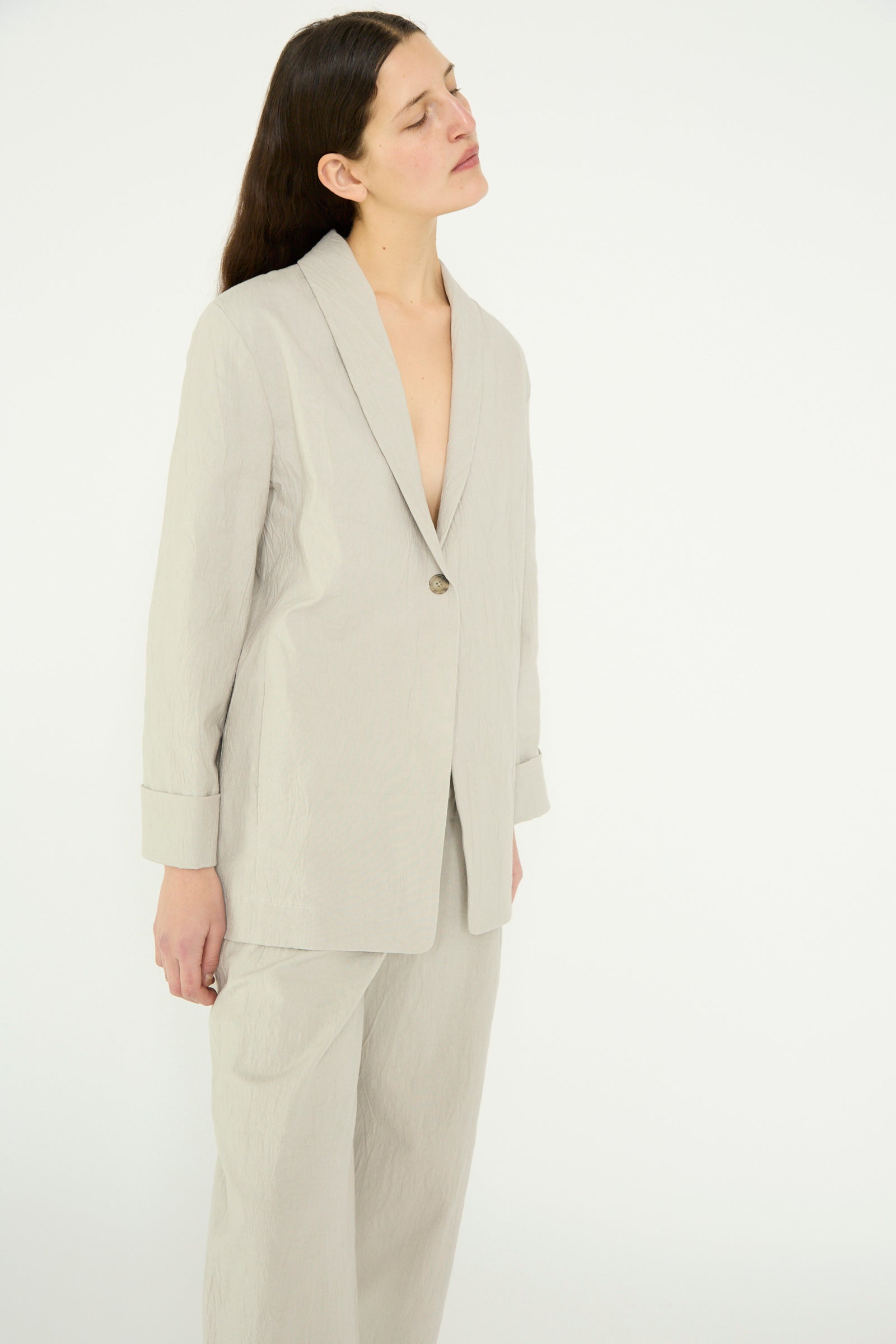 A person with eyes closed, wearing Lauren Manoogian's oversized Texture Blazer in Pewter, standing against a plain white background.