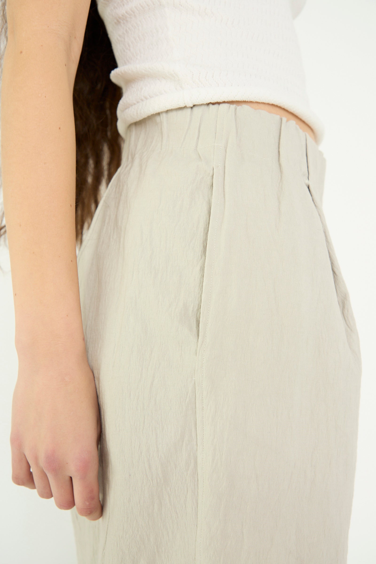 Close-up of a person wearing Lauren Manoogian's Texture Trouser in Pewter, featuring a white textured top and high-waisted, wide-leg design. The image focuses on the side, highlighting the crinkled cotton blend texture of the clothing.