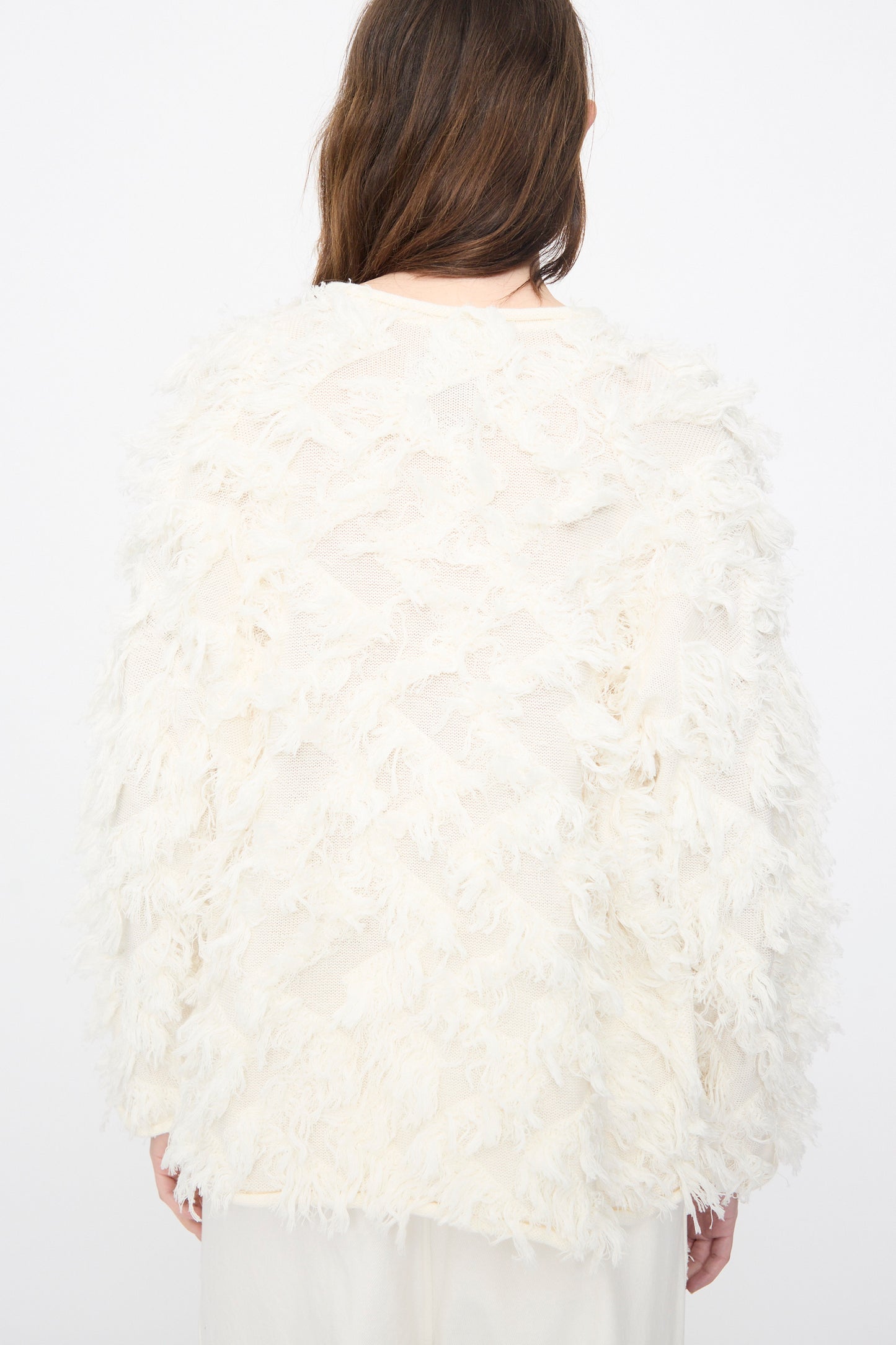 A person faces away, wearing the Lauren Manoogian Tufted Pullover in Bone with fringed details and matching off-white pants, set against a plain white background.
