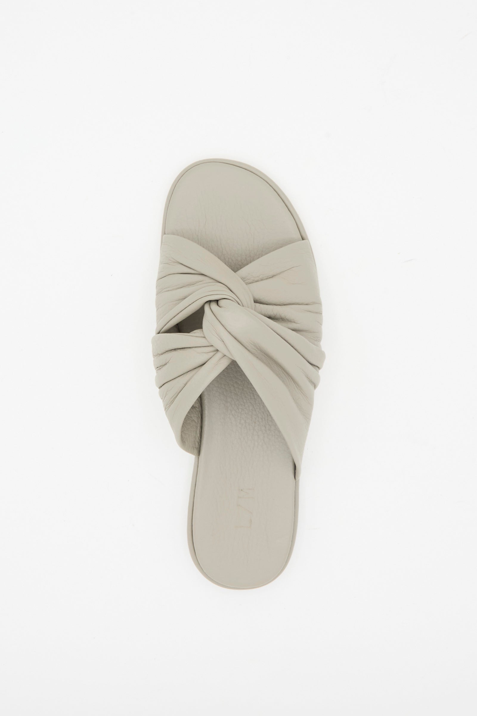 The Lauren Manoogian Twist Slide in Stone, a single light grey leather sandal with a twist vamp design, is photographed from above on a white background.