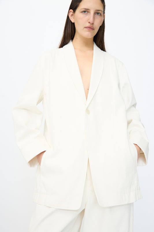 A person with long brown hair wears the Lauren Manoogian Washed Jacket in White, standing with hands in pockets against a plain white background.