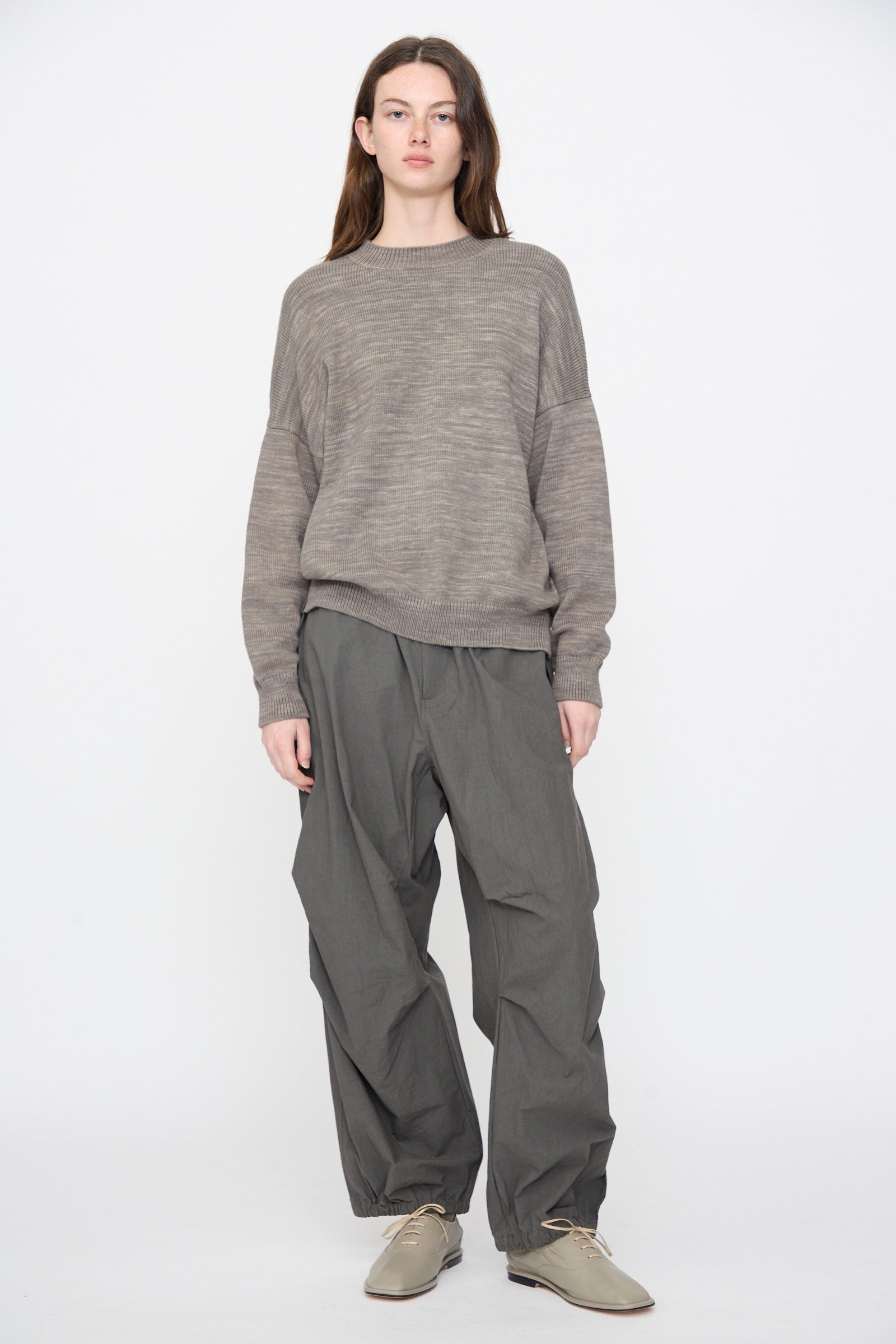 Woman in the Lauren Manoogian Watercolor Crewneck in Rock and charcoal grey voluminous pants, standing on a white background.